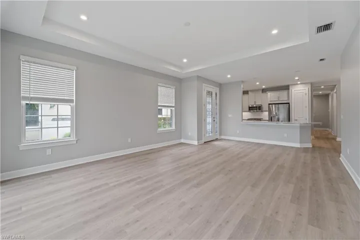 Unfurnished living room featuring a tray ceiling and light hardwood / wood-style flooring