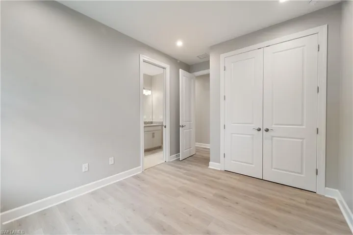 Unfurnished bedroom featuring light hardwood / wood-style floors, ensuite bathroom, and a closet
