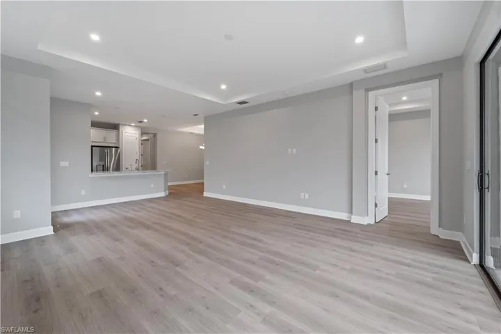 Unfurnished living room with light hardwood / wood-style floors and a tray ceiling