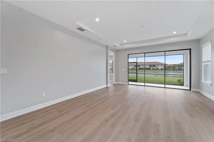 Spare room with a wealth of natural light, light hardwood / wood-style floors, and a tray ceiling