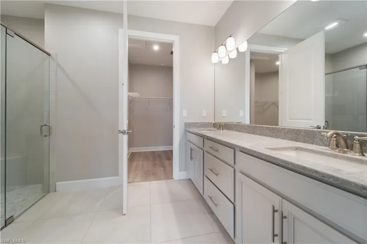Bathroom with a shower with shower door, vanity, and tile patterned flooring