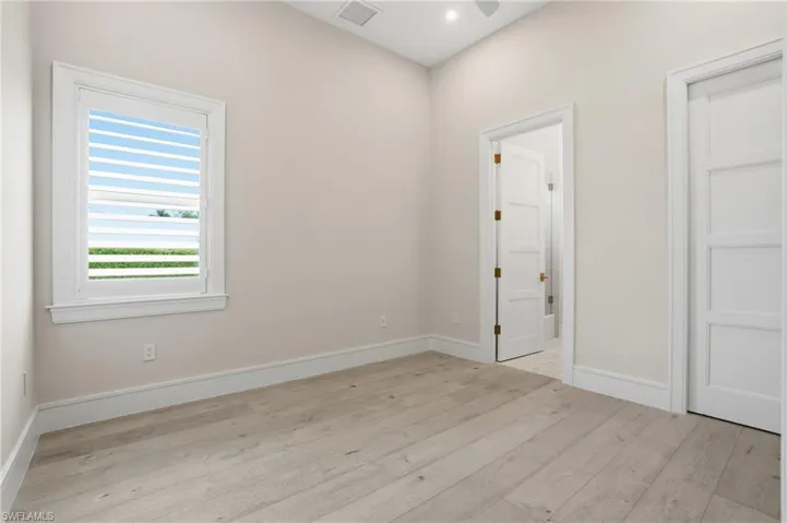 Unfurnished bedroom featuring light wood-style floors, ensuite bathroom, and recessed lighting
