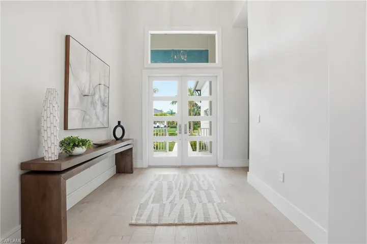 Entryway with french doors, a high ceiling, and light wood-style flooring