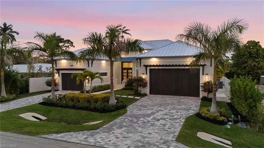 Contemporary home with a garage, decorative driveway, a standing seam roof, stucco siding, and a lawn