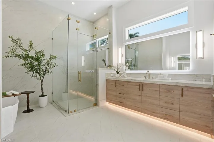 Full bathroom with vanity, a marble finish shower, a freestanding bath, light marble finish flooring, and recessed lighting