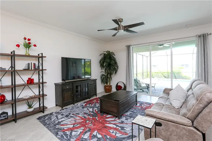 Tiled living room featuring ornamental molding, ceiling fan, and a healthy amount of sunlight
