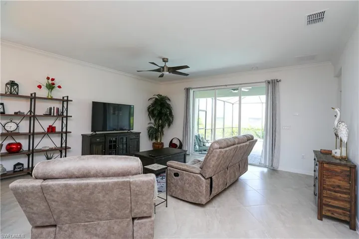 Living room with ornamental molding, ceiling fan, and light tile patterned floors