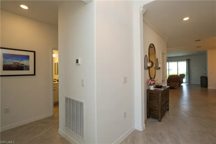 Hallway with ornamental molding and light tile patterned floors