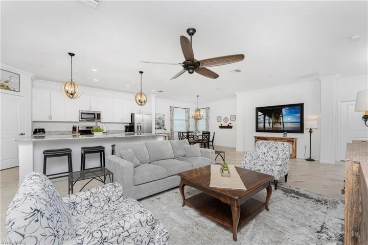 Living area with crown molding, recessed lighting, ceiling fan with notable chandelier, and visible vents