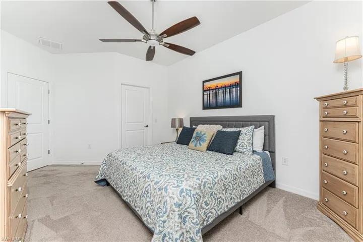 Bedroom featuring a ceiling fan, light colored carpet, visible vents, and baseboards
