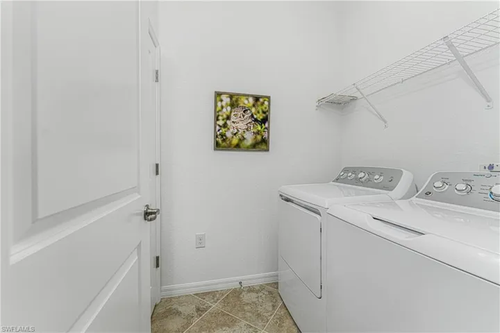 Laundry room featuring light tile patterned floors, baseboards, independent washer and dryer, and laundry area