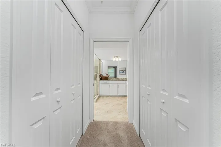 Hallway with light carpet and ornamental molding