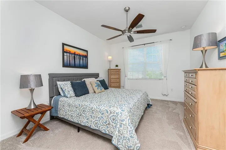 Bedroom with visible vents, light carpet, a ceiling fan, baseboards, and vaulted ceiling