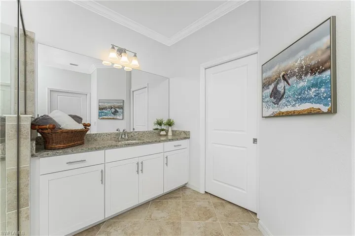 Bathroom featuring walk in shower, vanity, baseboards, and ornamental molding