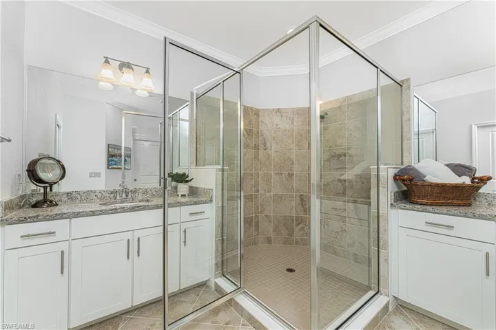 Bathroom with vanity, a stall shower, crown molding, and tile patterned flooring