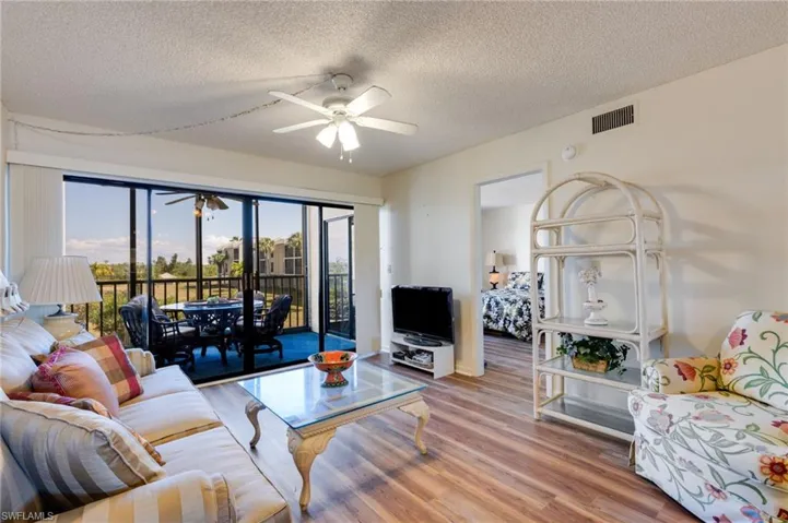 Living area with a ceiling fan, wood finished floors, and a textured ceiling