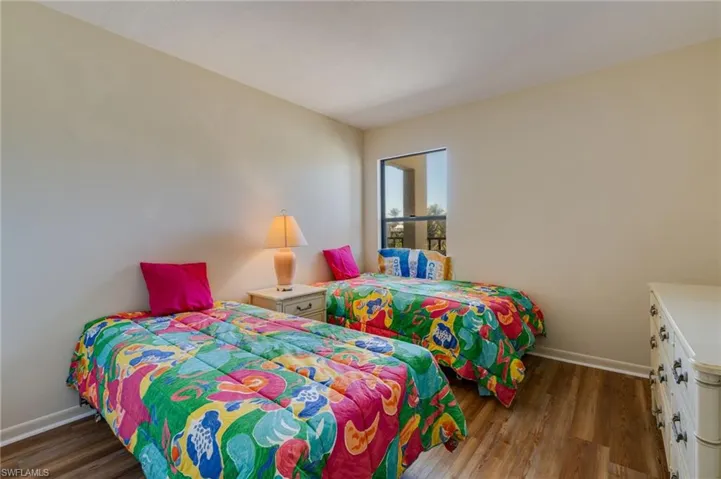 Bedroom with baseboards and dark wood-type flooring