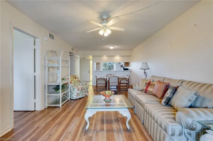 Living area with ceiling fan, wood finished floors, and a textured ceiling