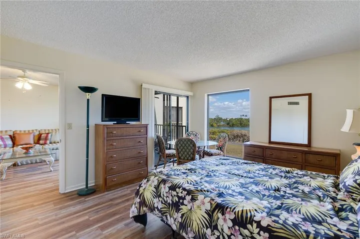 Bedroom with access to exterior, a textured ceiling, and wood finished floors