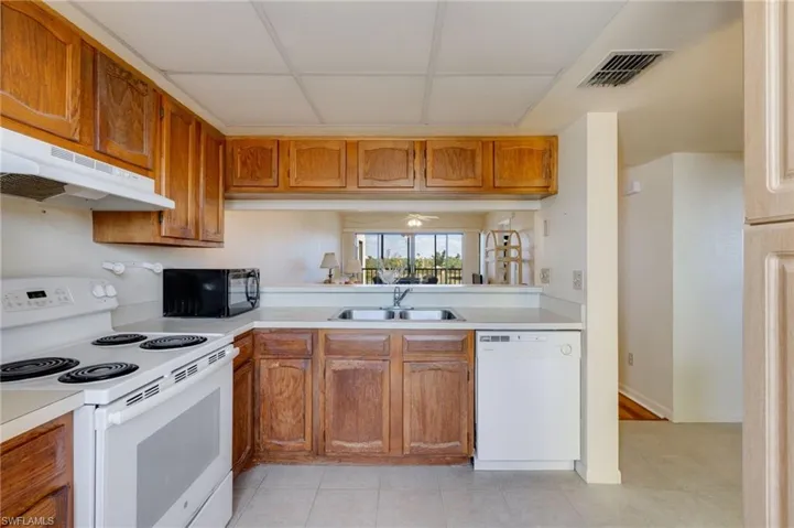 Kitchen with white appliances, wood finish cabinets, light countertops, and light tile patterned floors