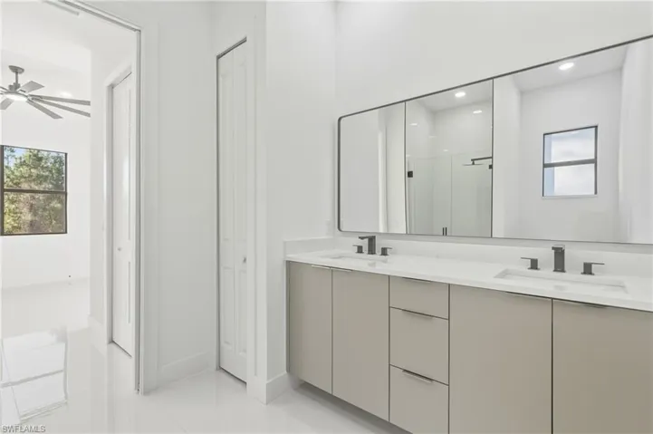 Bathroom with a closet, double vanity, a stall shower, recessed lighting, and a ceiling fan