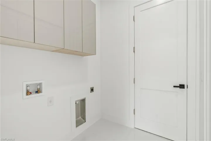 Laundry area with cabinet space, electric dryer hookup, washer hookup, and light tile patterned floors