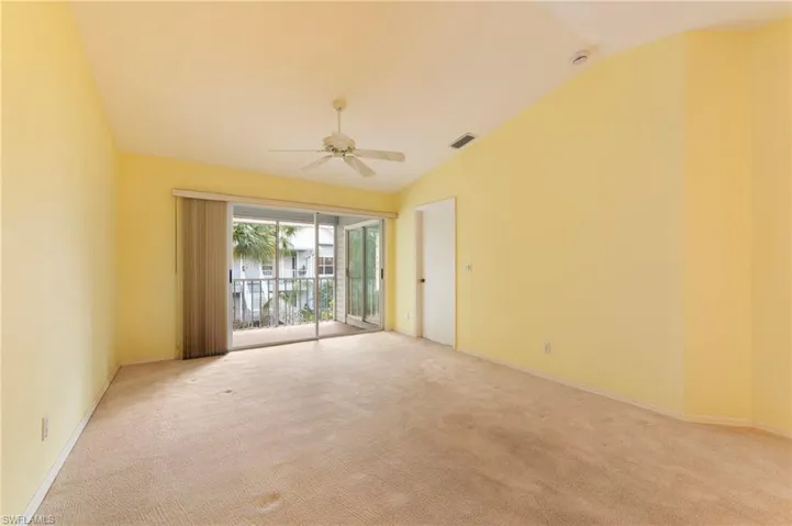 Empty room featuring lofted ceiling, ceiling fan, and light carpet