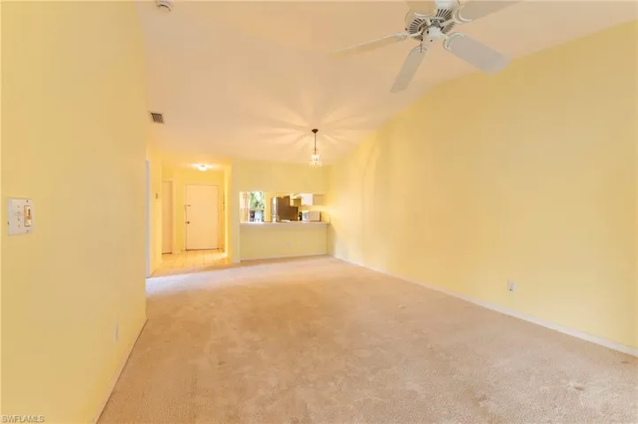 Unfurnished room featuring vaulted ceiling, light colored carpet, and a ceiling fan