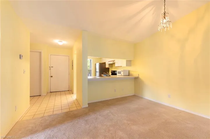 Unfurnished living room featuring light carpet and suspended lighting