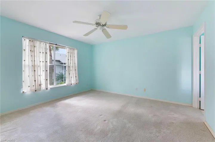 Primary bed room featuring light carpet, walk in closet and ceiling fan