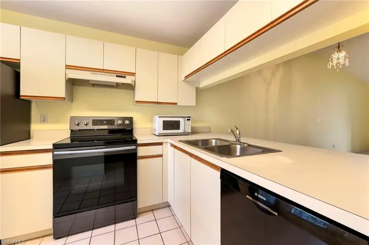 Kitchen featuring stainless steel electric stove, dishwasher, light countertops, and white microwave