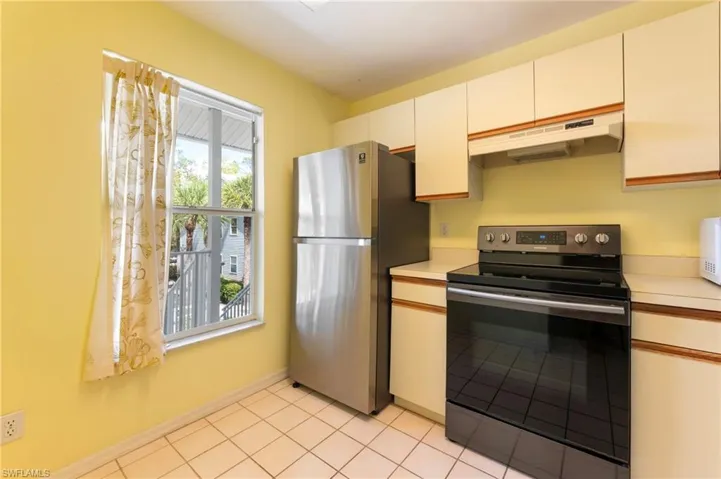 Kitchen with stainless steel appliances, light countertops, light tile patterned flooring, and white cabinets