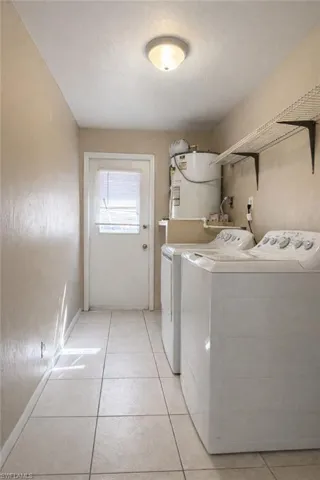 Laundry room with water heater, light tile patterned floors, and separate washer and dryer