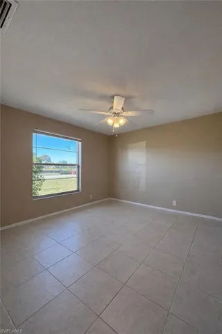Empty room featuring light tile patterned floors, ceiling fan, and a textured ceiling
