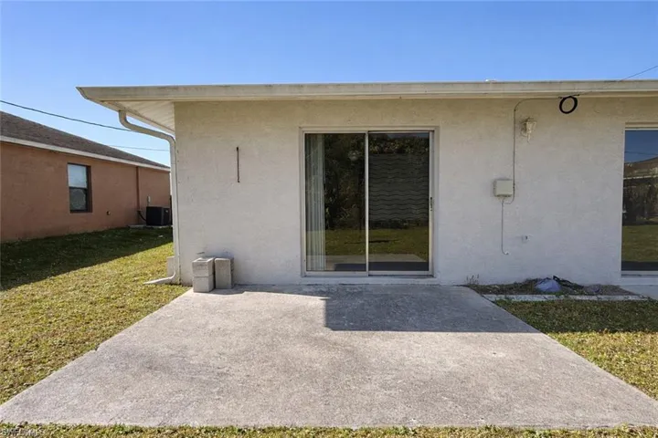Rear view of property with a patio, a yard, and stucco siding