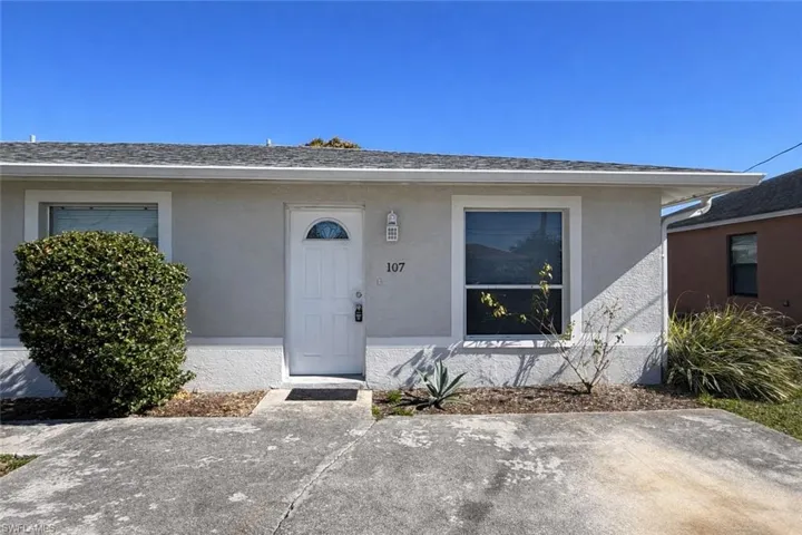 Property entrance with stucco siding and a shingled roof