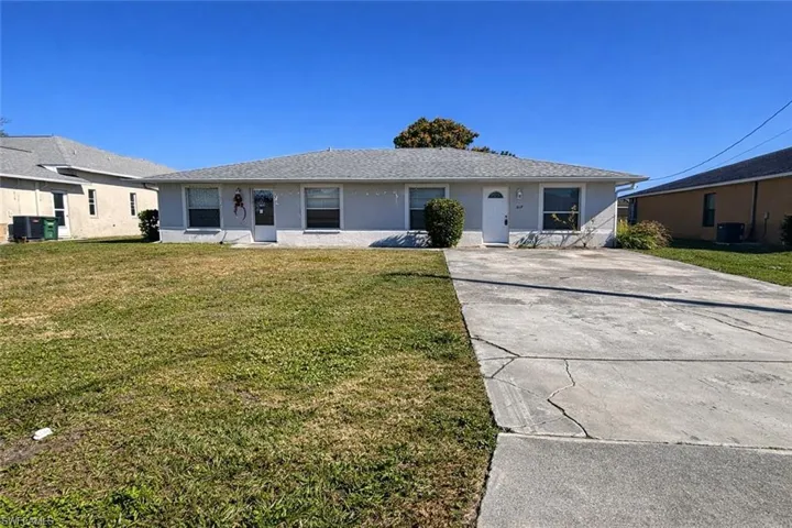 Ranch-style home featuring a front yard, stucco siding, and concrete driveway
