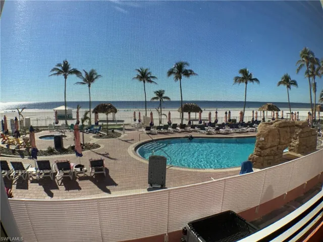 This balcony overlooks buildings  pool, hot tub and beach front on the Gulf