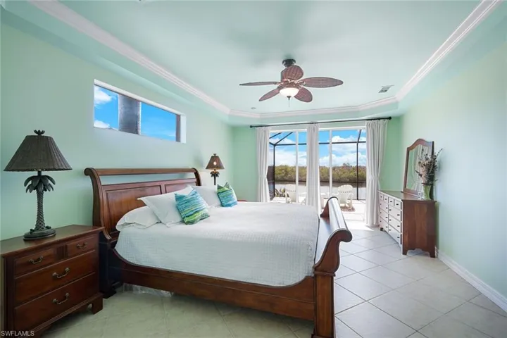 Spacious primary bedroom with access to the screened lanai and pool area