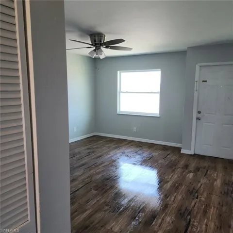 Unfurnished room with ceiling fan and dark wood-type flooring