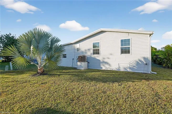 Back View of home's exterior featuring a lawn and a central AC unit