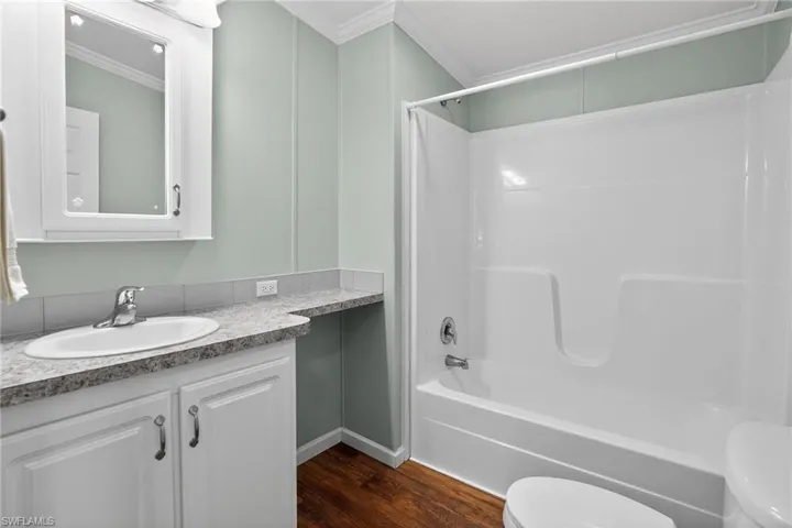 Full hall bathroom with crown molding, vanity, shower / tub combination, and dark wood finished floors