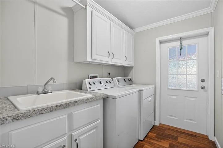 Laundry room with dark wood-style floors, independent washer and dryer, crown molding, and cabinet space & sink!
