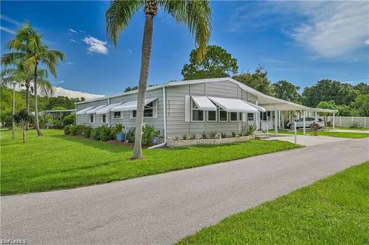 Manufactured / mobile home with driveway, a front lawn, and an attached carport