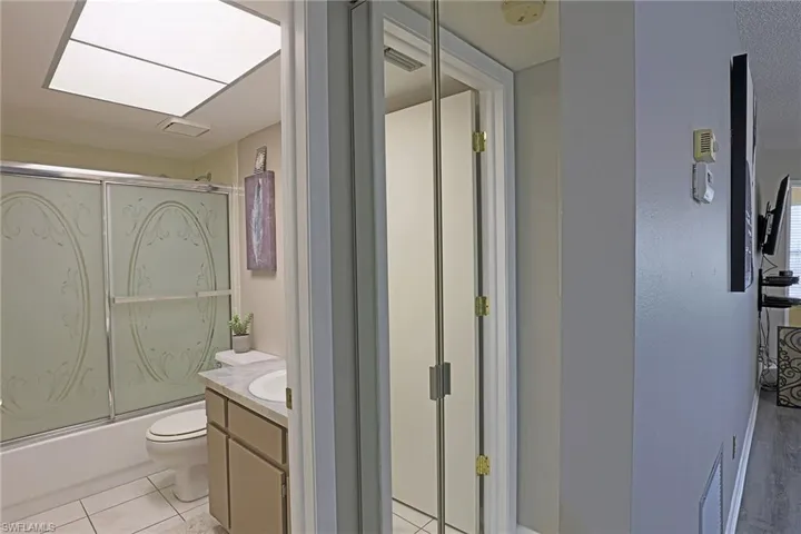 Bathroom with toilet, vanity, combined bath / shower with glass door, and tile patterned floors