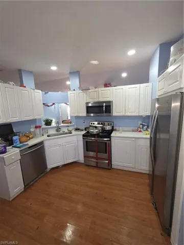 Kitchen featuring stainless steel appliances, white cabinets, light countertops, and recessed lighting