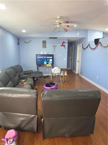 Living area with wood finished floors, a ceiling fan, lofted ceiling, and recessed lighting