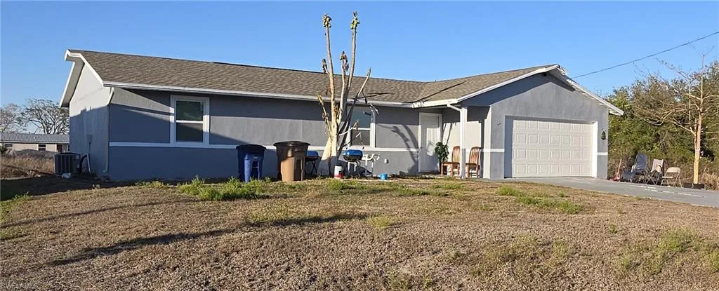 View of front facade with a garage, a shingled roof, driveway, and stucco siding
