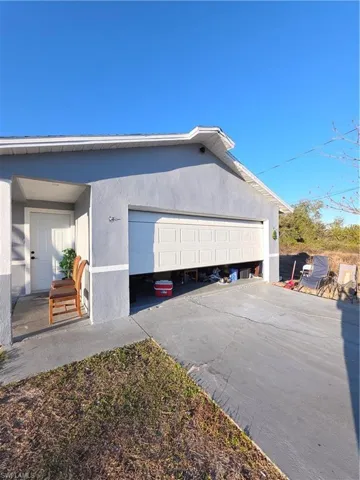 View of side of home with stucco siding, driveway, and an attached garage