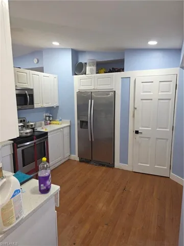 Kitchen featuring stainless steel fridge with ice dispenser, white cabinets, dark wood finished floors, range, and recessed lighting
